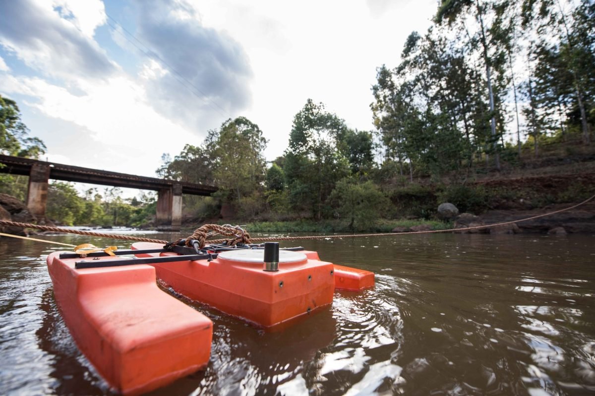 Gauge monitoring station at Gura River. The WARMA team, who have partnered with the NWF, come at least once a month with their equipment to measure water quality (sediment levels), water quantity (volumn) and use a Acoustic Doppler Current Profiler (ADCP)- the boat looking tool-to measure the depth, width and flow of the water. WARMA employs 2 locals to measure the water levels twice a day using the water stick. WARMA team: Faith Mbathi (wearing waders), Jane Njoroge (big hair), Wangombe Thuku (bearded man), Michael Muthoro (computer guy).